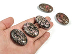 Rhodonite palm gemstone spa stone, 45x35mm, from GemstoneGO, showing smooth, polished surface with vibrant pink and black patterns.