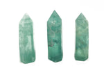 Green fluorite obelisk tower crystal from GemstoneGO, showcasing a polished green gemstone with a pointed tip and smooth surfaces.
