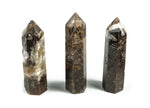 Ribbed obelisk tower crystal in clear gemstone with textured ribbed surface, displayed on a plain background.