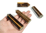 Tiger Eye obelisk tower crystal from GemstoneGO with polished, golden-brown bands and a pointed tip, showcasing natural stone patterns.