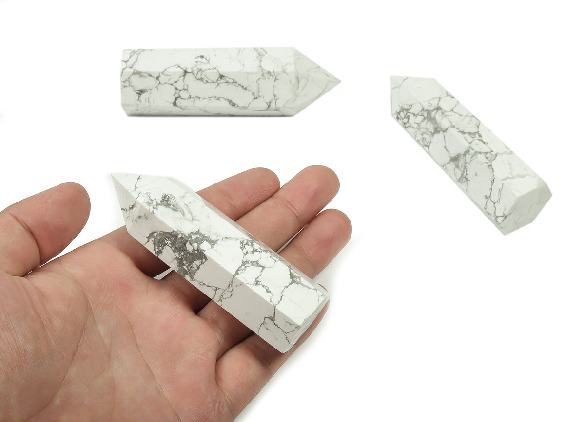 Howlite obelisk tower crystal from GemstoneGO, showcasing a smooth white stone with gray veining on a dark background.