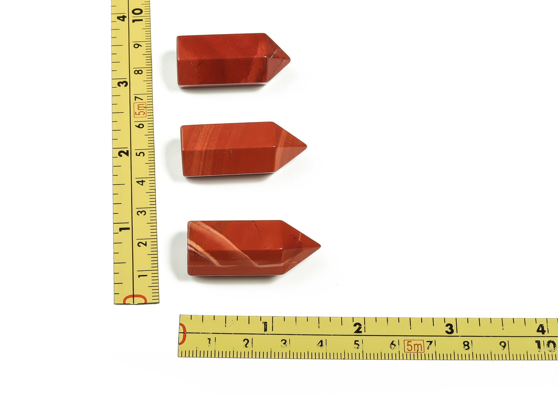 Red Jasper obelisk tower crystal, 35mm, from GemstoneGO, showing a vibrant red stone carved into a tall, pointed shape.