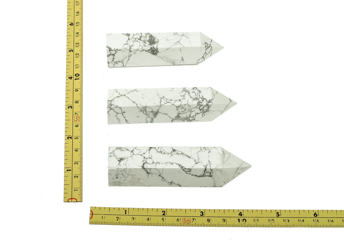 Light gray Howlite obelisk tower crystal from GemstoneGO, with polished surface and pointed top for decorative display.