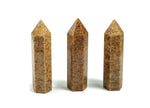 Golden silk jade obelisk tower crystal from GemstoneGO featuring a polished, golden-hued jade gemstone shaped into a tall obelisk.