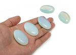 Opalite palm gemstone spa stone, 45x35mm, smooth oval shape with a glowing, milky appearance, used for relaxation and healing.