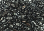 Black tourmaline crystal chips in semi-tumbled 7-12mm size, shown in bulk with irregular black stone pieces from GemstoneGO
