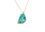 Turquoise crystal pendant with healing stones, featuring a silver setting, displayed on a neutral background.