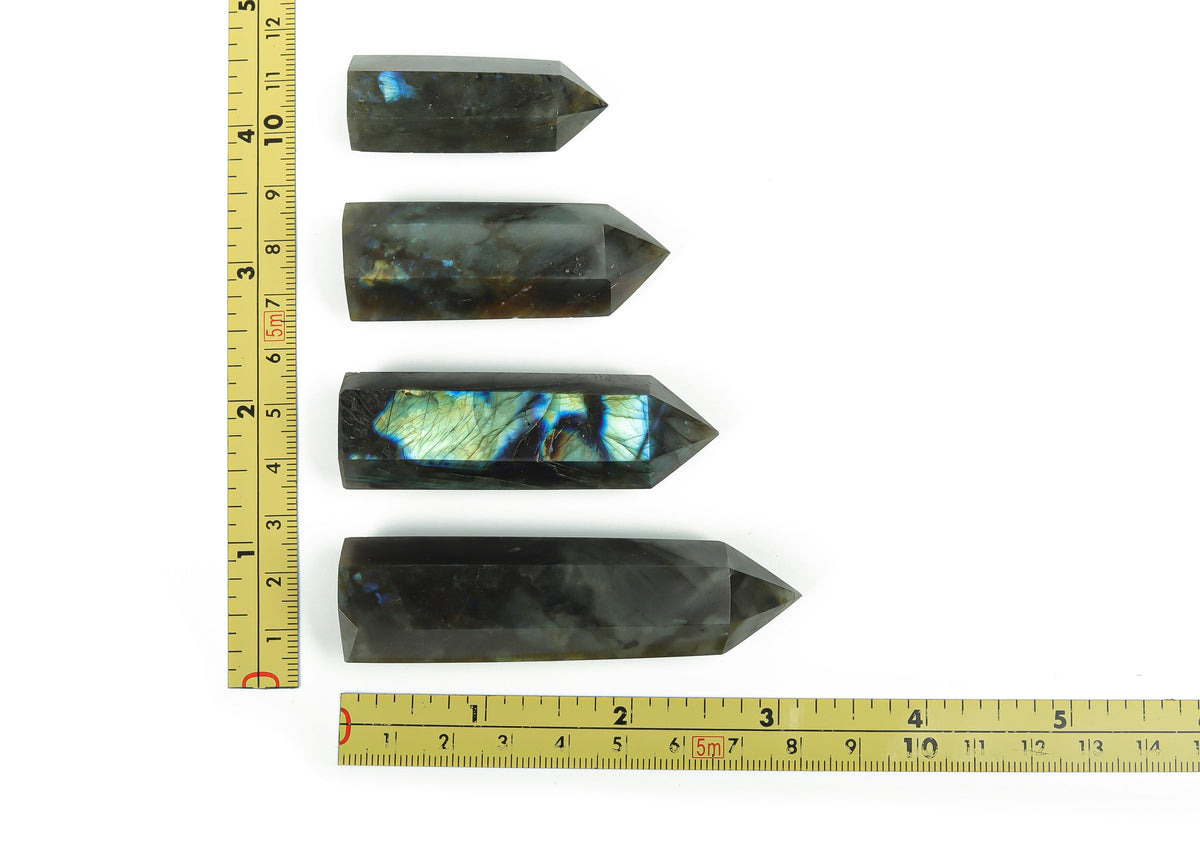Labradorite obelisk tower crystal from GemstoneGO showing iridescent gray and blue hues, polished geometric shape with natural stone texture.