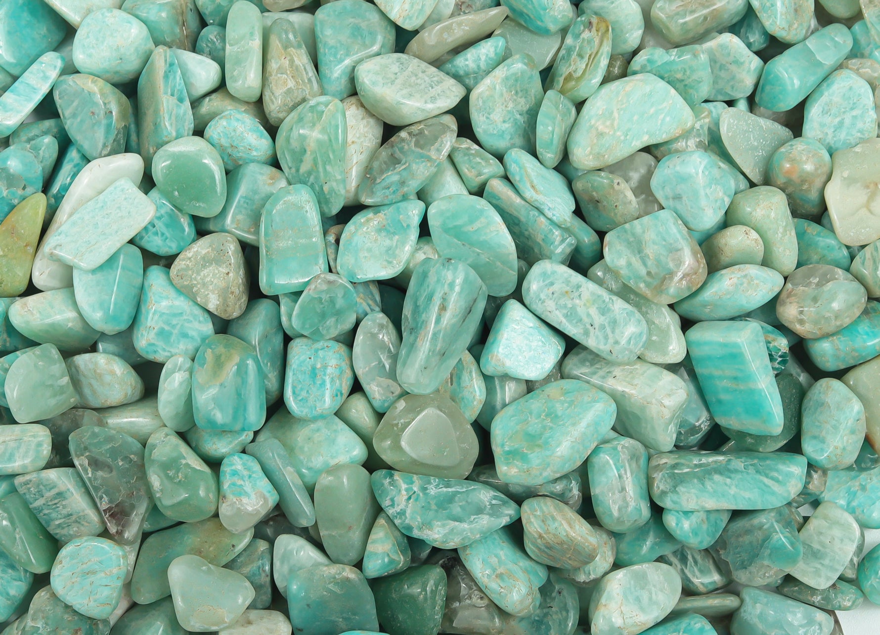 Close-up of Amazonite crystal chips, semi-tumbled stones in 7-12mm size, showcasing blue-green mineral with natural variations.
