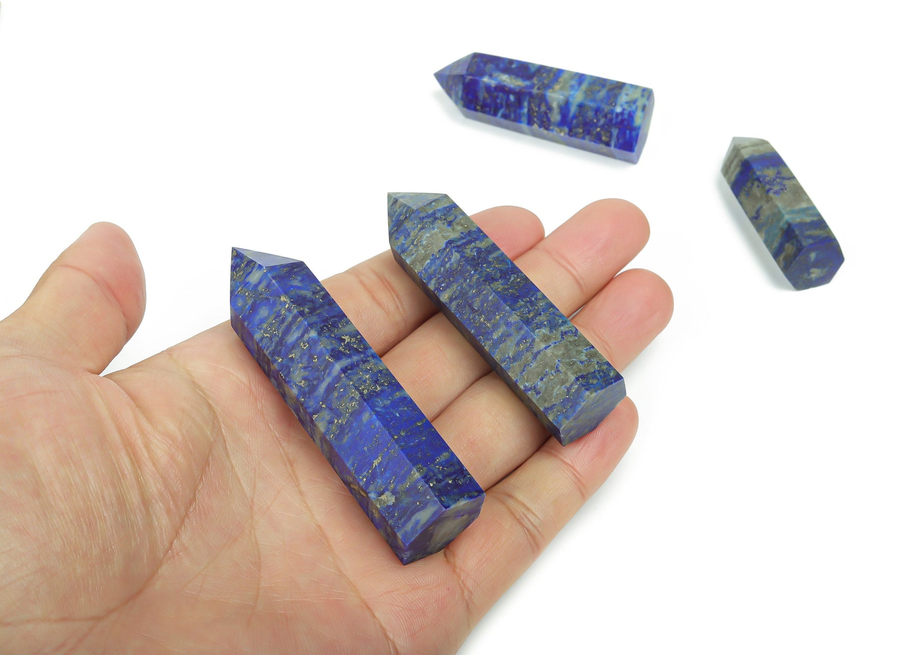 Lapis Lazuli obelisk tower crystal from GemstoneGO, showcasing deep blue stone with gold and white flecks on a plain background.