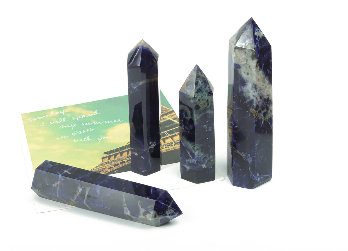 Sodalite obelisk tower crystal from GemstoneGO with deep blue and white mineral patterns, standing upright on a flat surface.