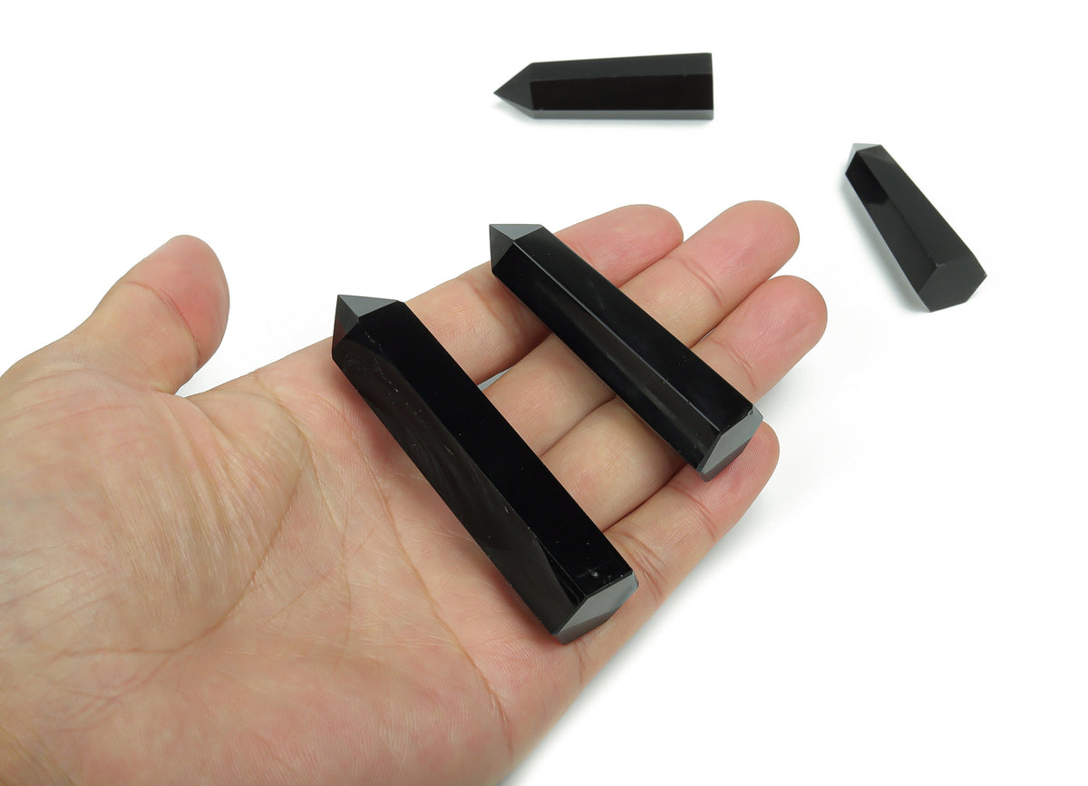 Dark obsidian obelisk tower crystal from GemstoneGO with a smooth, polished surface and pointed top, showcasing natural stone texture.