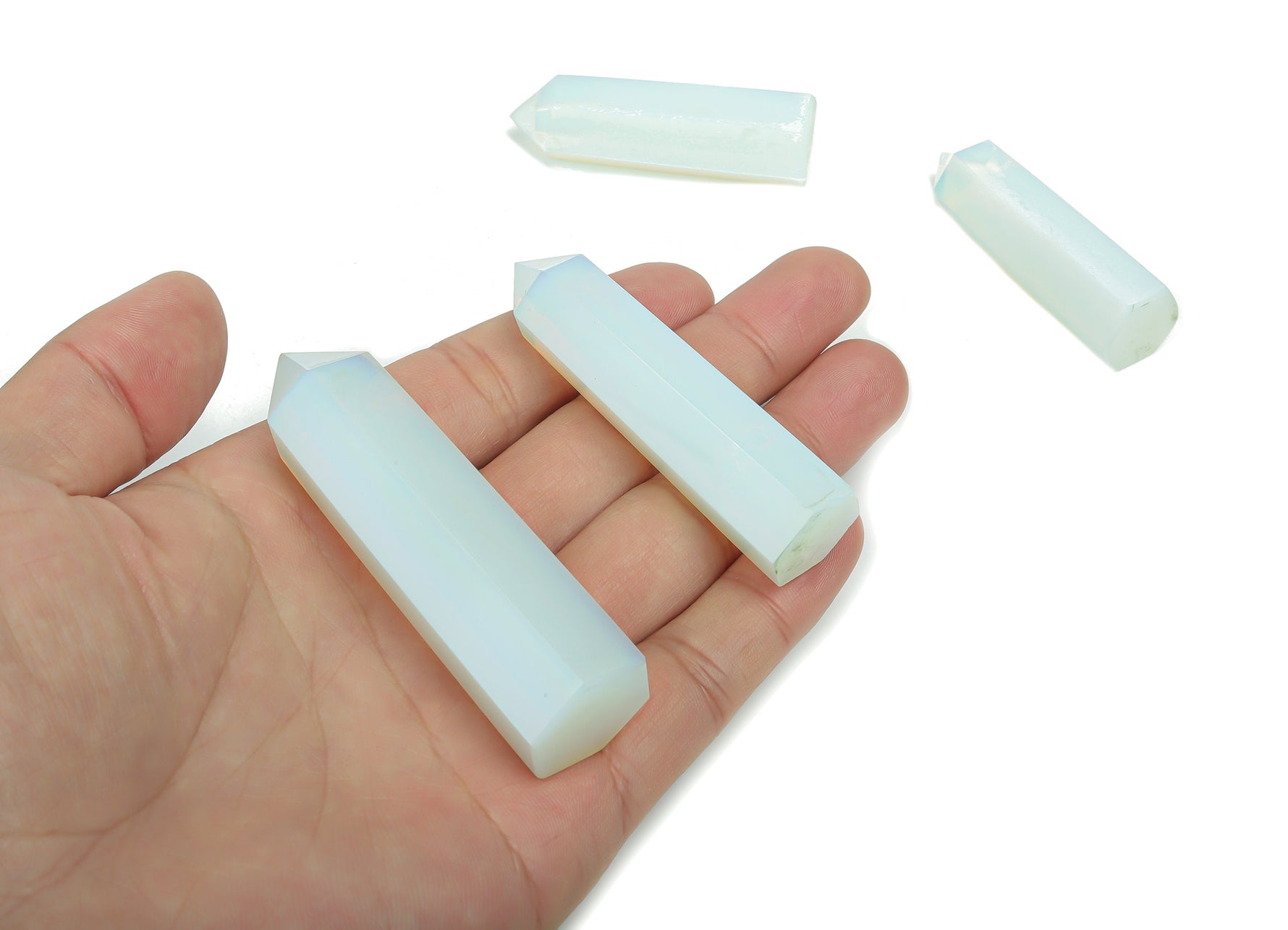 Opalite obelisk tower crystal from GemstoneGO, smooth translucent white gemstone with a pointed top, on a neutral background.