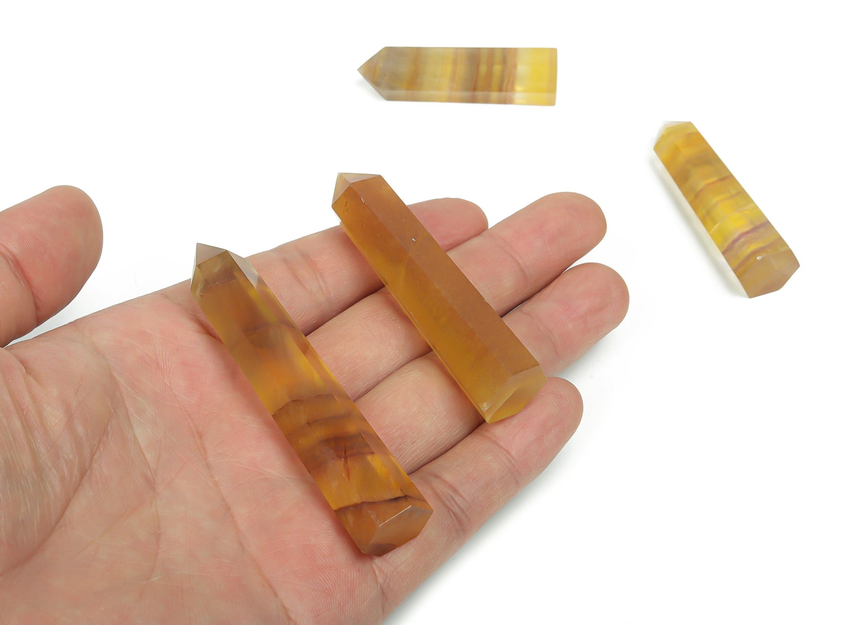 Yellow fluorite obelisk tower crystal from GemstoneGO, showcasing a polished yellow fluorite crystal with natural banding and a pointed tower shape.