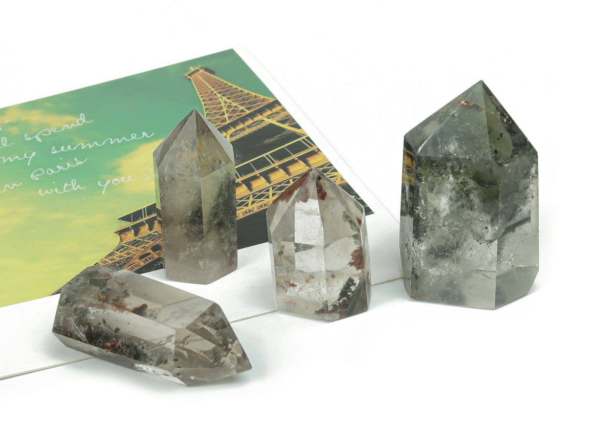 Lodolite Garden Quartz obelisk tower crystal from GemstoneGO with clear and smoky inclusions, standing upright on a white background.