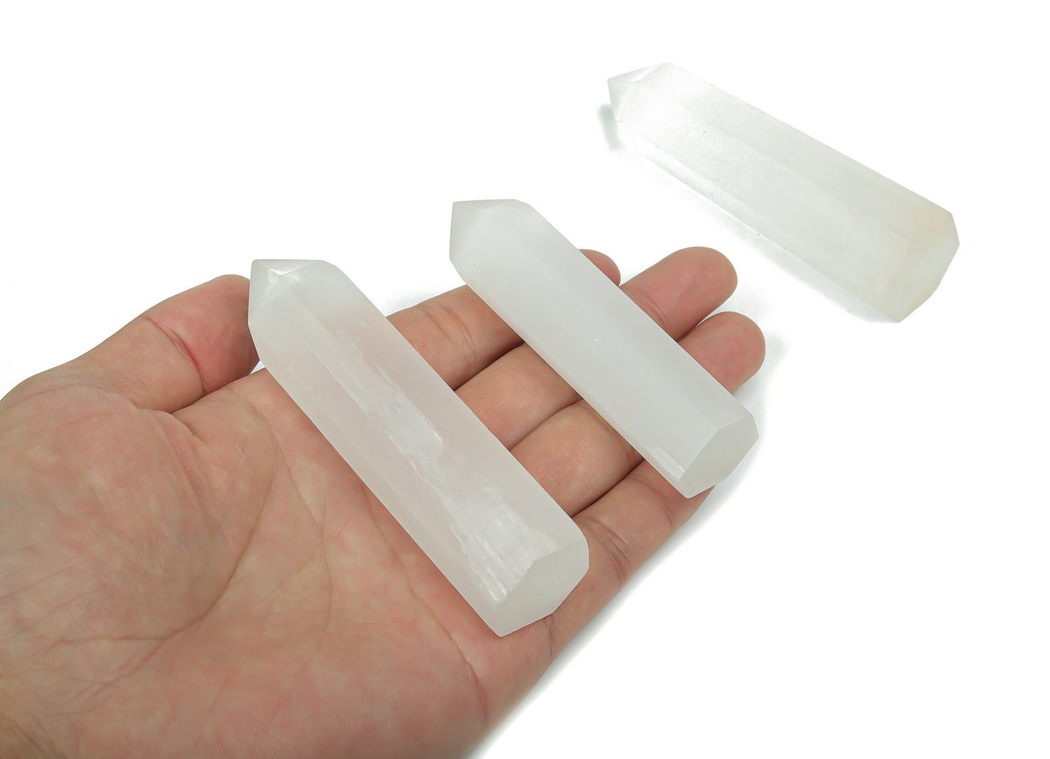 Selenite obelisk tower crystal by GemstoneGO, showing smooth white crystal with natural striations and a pointed tip.