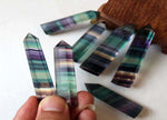 Rainbow fluorite obelisk tower crystal from GemstoneGO, showcasing vibrant multicolored crystal points on a polished base.