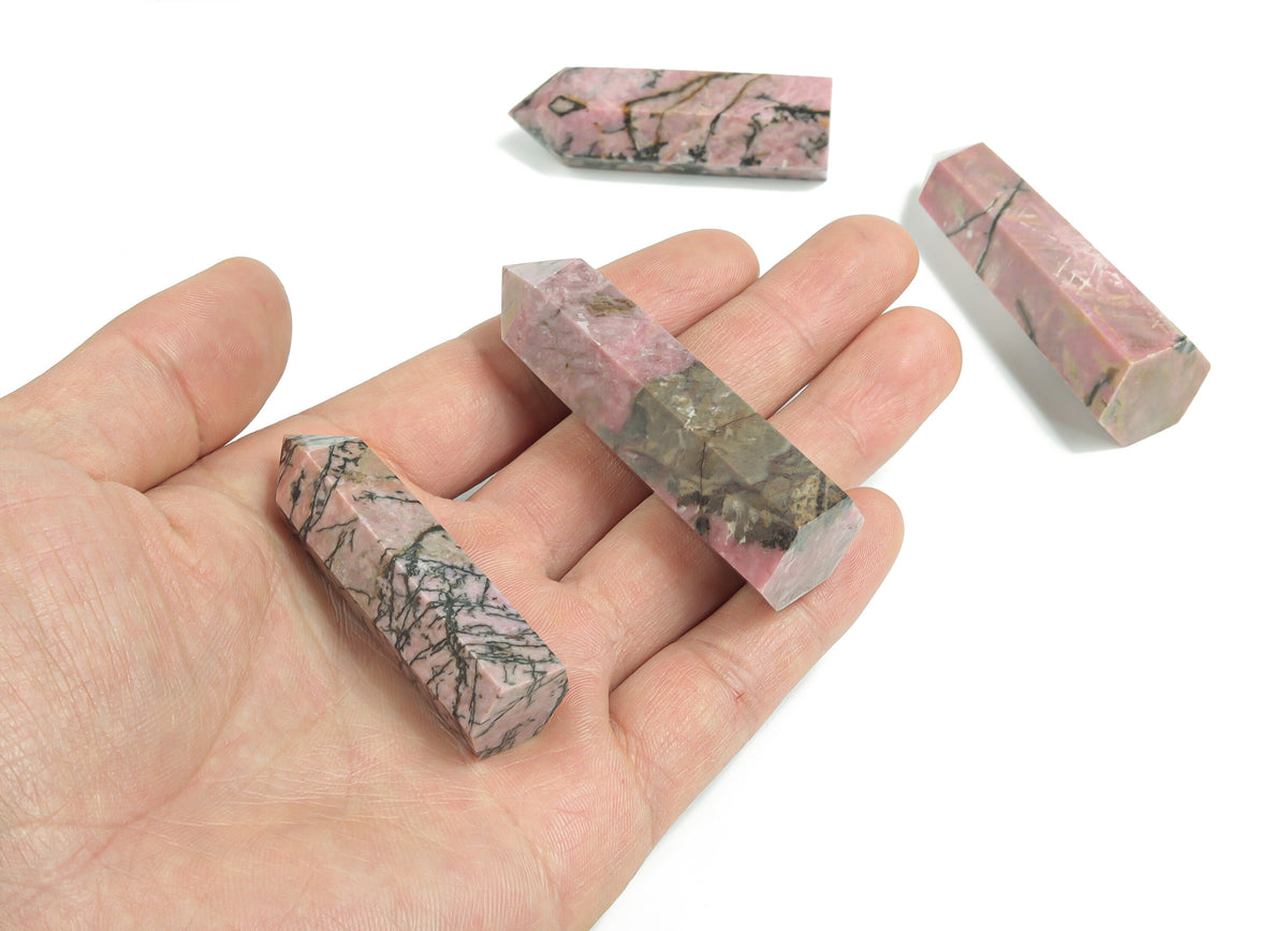 Rhodonite obelisk tower crystal from GemstoneGO, featuring pink and black mineral patterns on a polished stone surface.