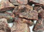 Raw garnet gemstone from GemstoneGO with deep red color and rough, uncut surface, showcasing natural mineral formation.