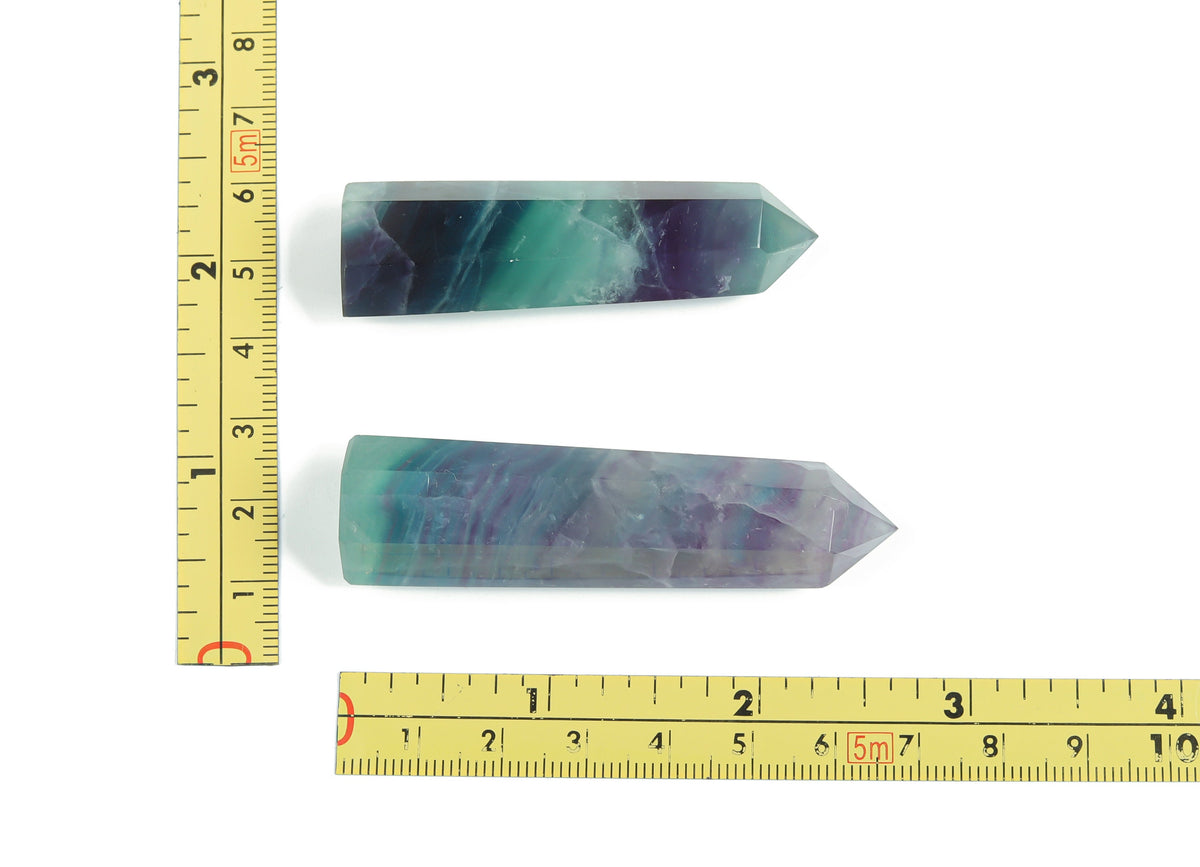 Blue fluorite obelisk crystal tower from GemstoneGO, polished gemstone with vibrant blue and green hues, standing upright on a flat surface.