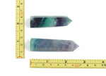 Blue fluorite obelisk crystal tower from GemstoneGO, polished gemstone with vibrant blue and green hues, standing upright on a flat surface.
