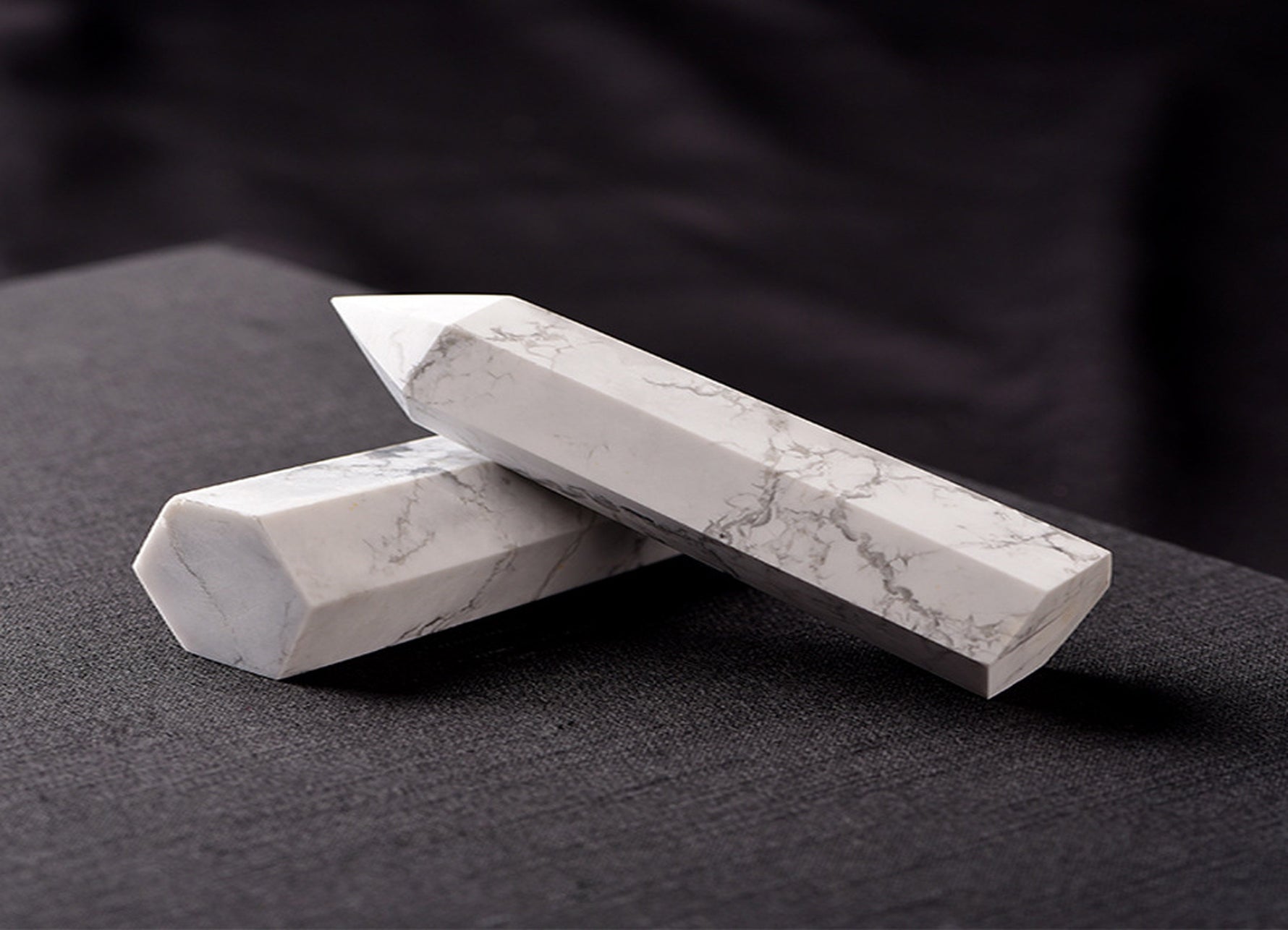 Howlite obelisk tower crystal from GemstoneGO, showcasing a smooth white stone with gray veining and a pointed top.