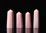 Pink Opal obelisk tower crystal from GemstoneGO with smooth polished surface and natural pink hue on a plain background.