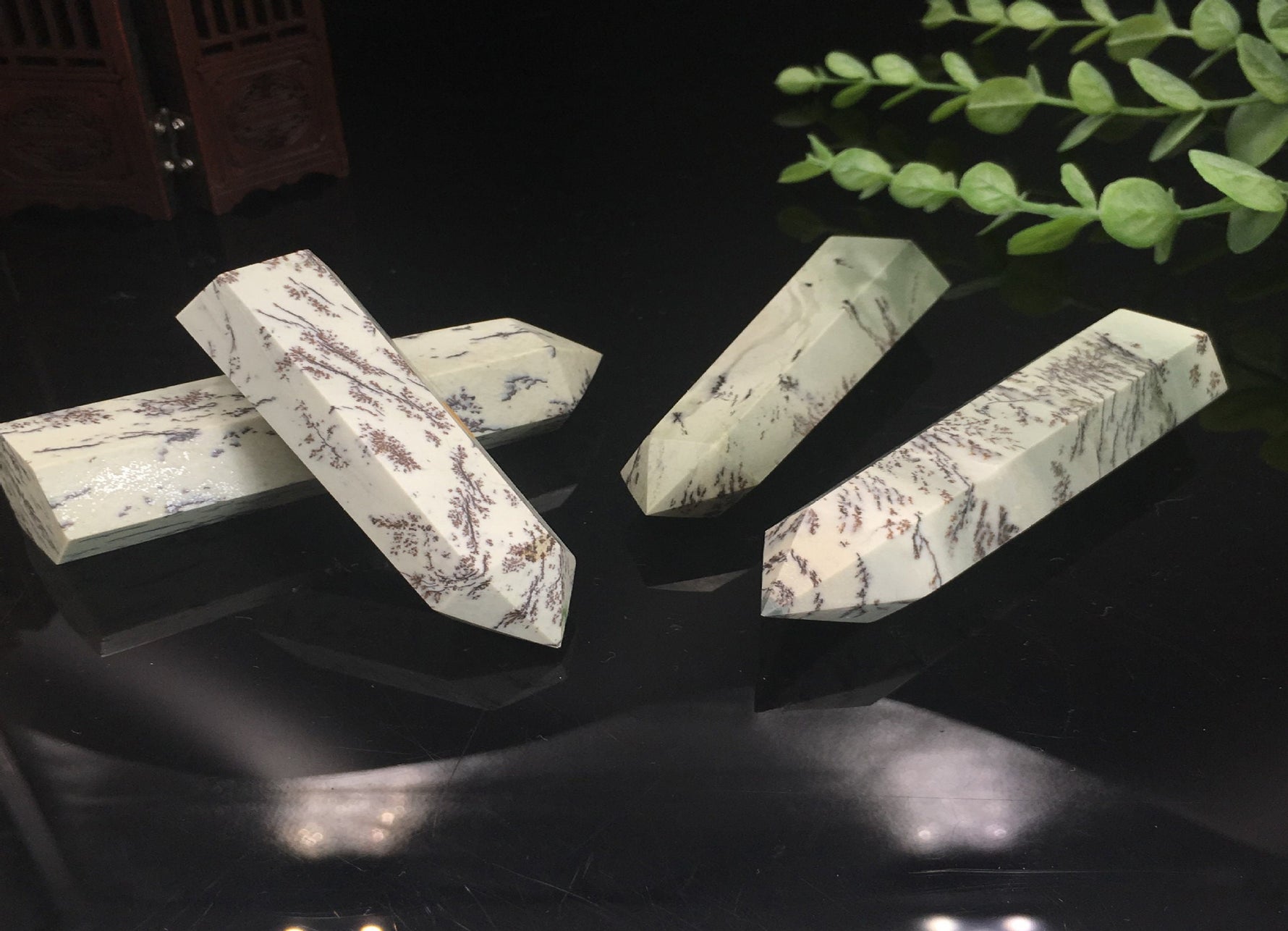 Dendritic jade obelisk tower crystal from GemstoneGO showing a green jade stone with natural dendritic patterns and a pointed shape.