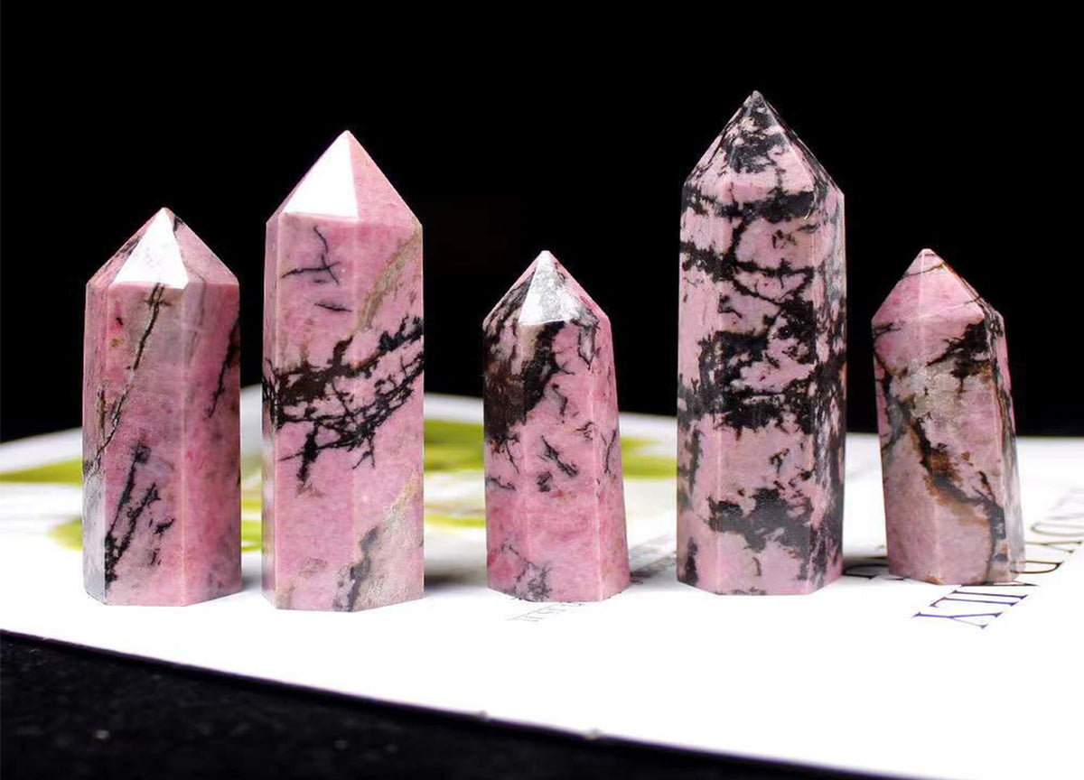 Rhodonite obelisk tower crystal from GemstoneGO showing a pink and black mineral stone with natural striations and polished surface.
