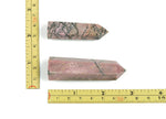 Rhodonite obelisk tower crystal from GemstoneGO showcasing a pink and black mottled mineral sculpture on a white background.