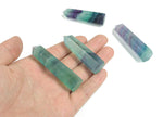 Polished fluorite obelisk tower crystal from GemstoneGO, showcasing vibrant green and purple mineral banding on a white background.