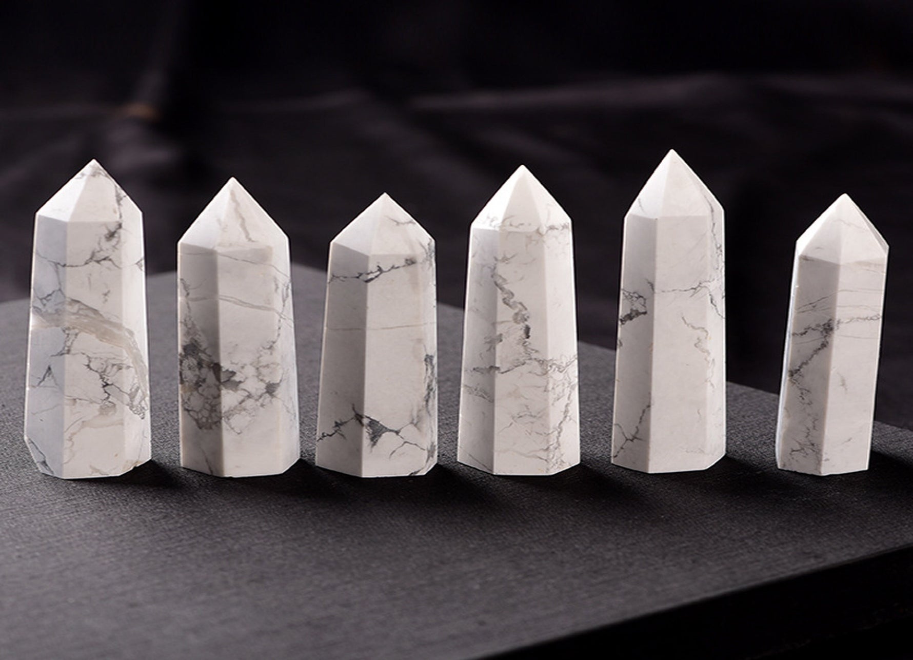 Howlite obelisk tower crystal from GemstoneGO, showcasing a smooth white stone with gray veining on a clear base.