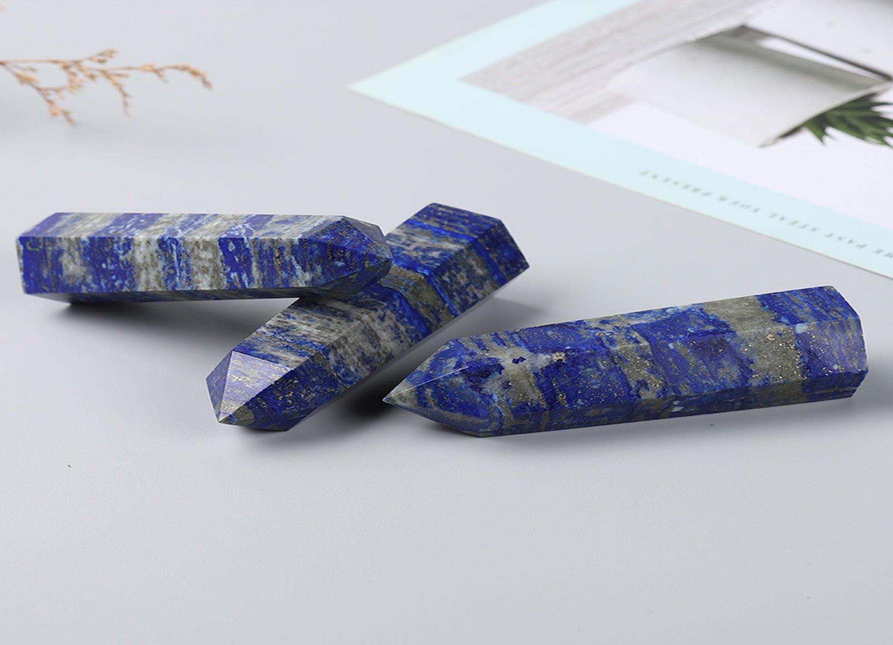 Lapis Lazuli obelisk tower crystal from GemstoneGO, showcasing deep blue stone with golden pyrite inclusions on a white background.