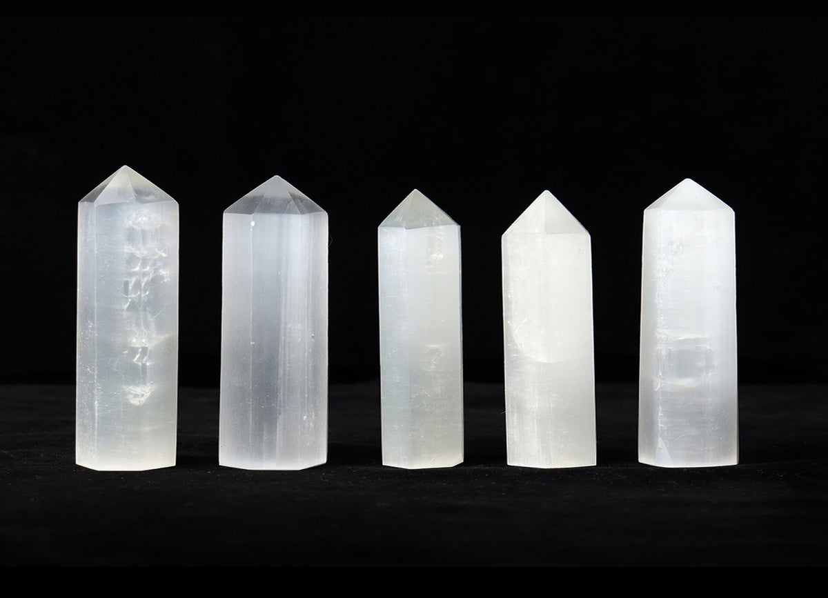 Selenite obelisk tower crystal from GemstoneGO, white translucent mineral with smooth polished surface and pointed tip.