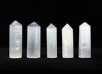 Selenite obelisk tower crystal from GemstoneGO, white translucent mineral with smooth polished surface and pointed tip.