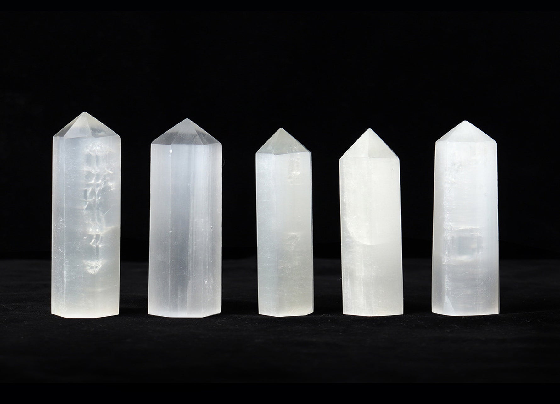 Selenite obelisk tower crystal from GemstoneGO, white translucent mineral with smooth polished surface and pointed tip.