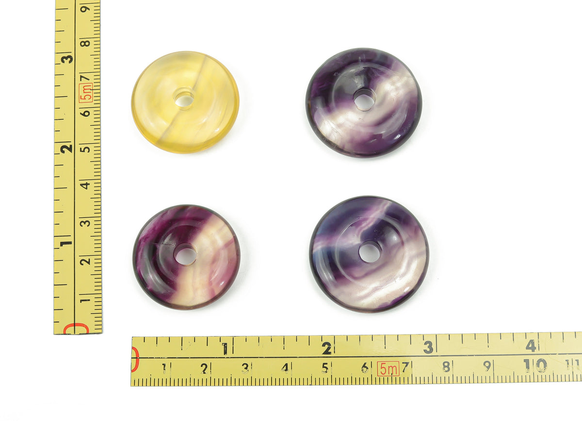 Polished 30mm fluorite crystal donut from GemstoneGO, showcasing vibrant purple and green swirling patterns, natural gemstone appearance.