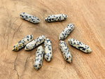Dalmatian Jasper carved terminated point gemstone, 33mm, from GemstoneGO, showcasing black spots on a cream background.