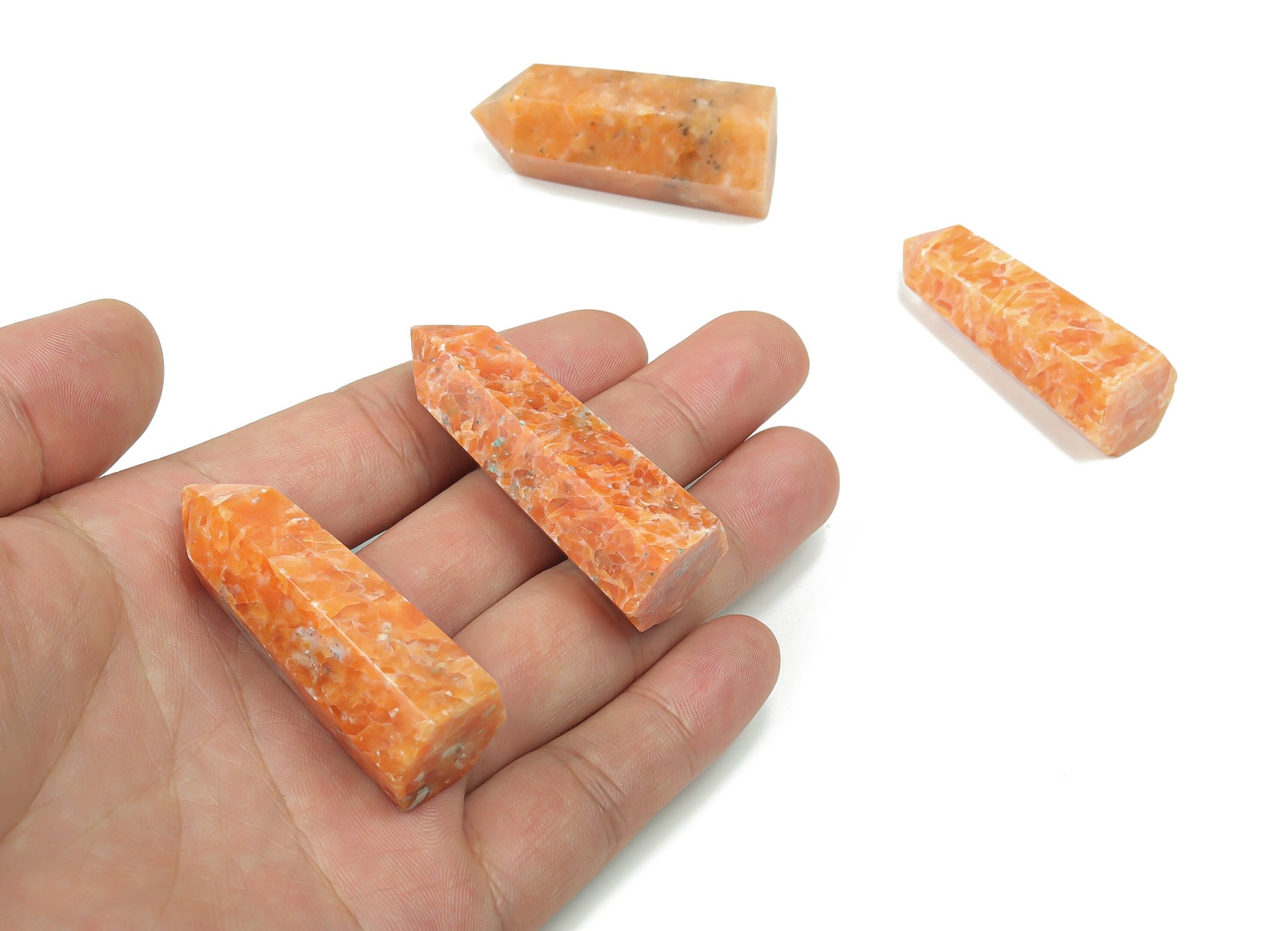 Sunstone obelisk tower crystal from GemstoneGO, showcasing warm orange hues and natural stone texture on a white background.