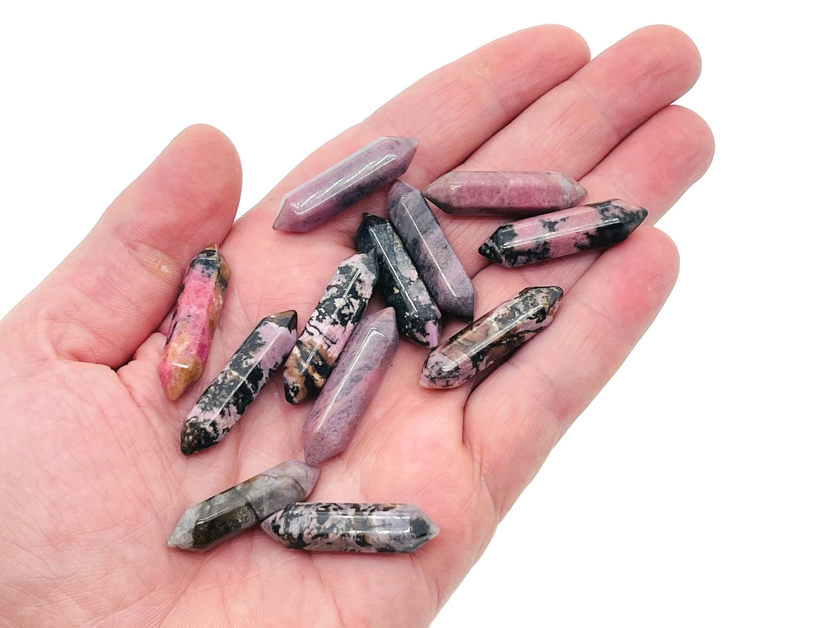 Rhodonite terminated carved crystal point, 33mm, from GemstoneGO showing polished pink and black mineral patterns.