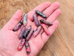 Rhodonite terminated carved crystal point, 33mm, from GemstoneGO, showcasing pink and black stone with smooth pointed tip.