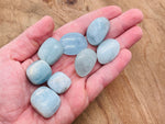 Polished aquamarine tumbled stone from GemstoneGO, showcasing vibrant blue-green color and smooth, rounded surface.