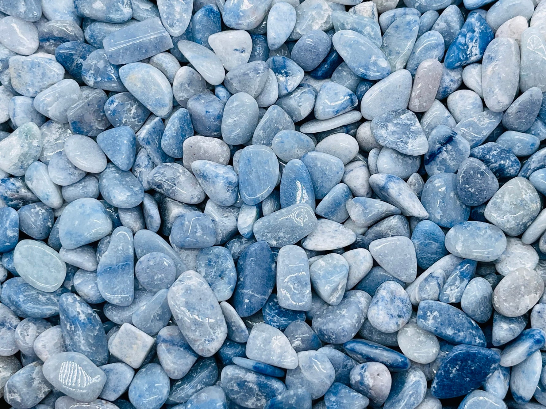 Blue aventurine crystal chips in 5-7mm semi-tumbled stones, shown in bulk with vibrant blue color and smooth, irregular shapes.