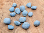 Angelite tumbled stone from GemstoneGO, showing smooth, light blue mineral with natural patterns and glossy polished finish.