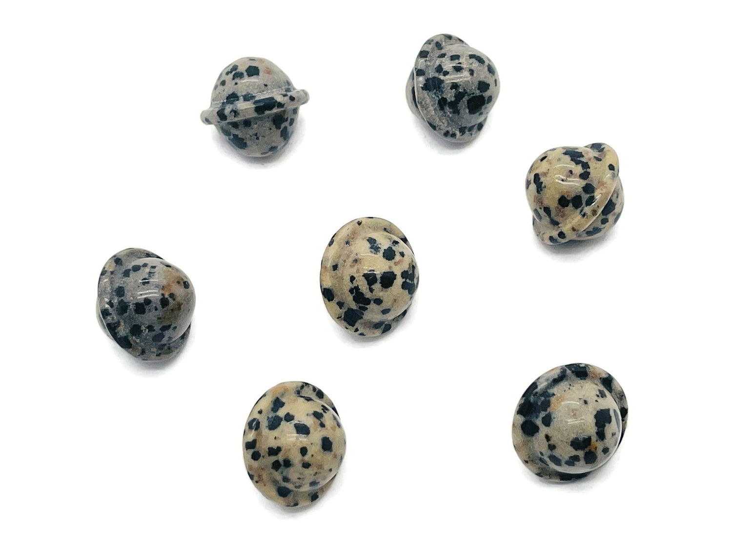 Dalmatian Jasper Saturn crystal carved as a mini planet gemstone, 18mm, showcasing black spots on a cream background.