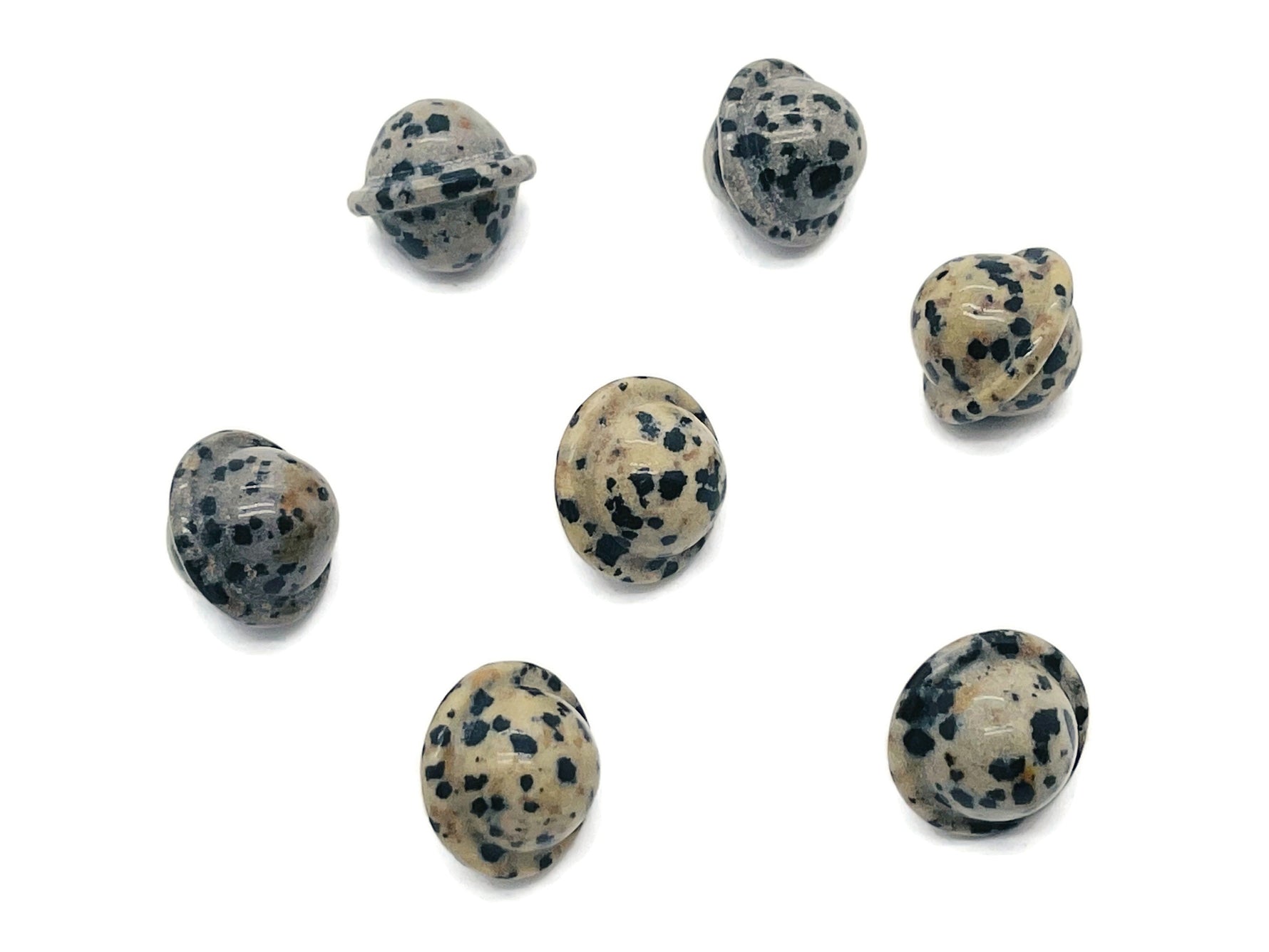 Dalmatian Jasper Saturn crystal carved as a mini planet gemstone, 18mm, showcasing black spots on a cream background.