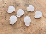 Clear quartz skull carved gemstone, 25mm size, featuring detailed craftsmanship and smooth polished surface.