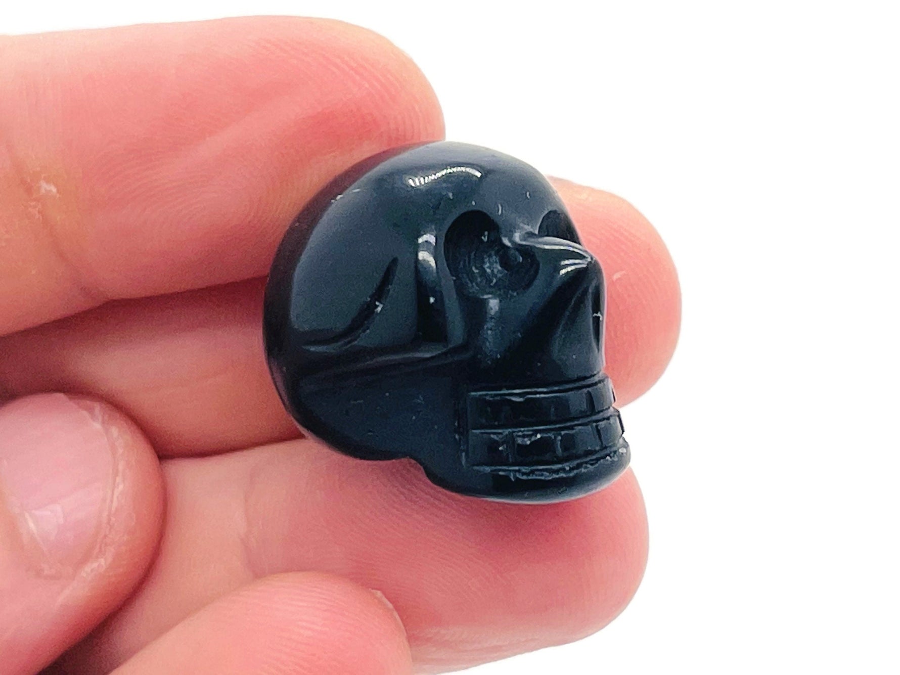 Carved 25mm obsidian gemstone skull with detailed features, showcasing a smooth, polished black stone design.