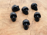 Carved 25mm obsidian skull gemstone from GemstoneGO showing detailed black stone carving on a white background.