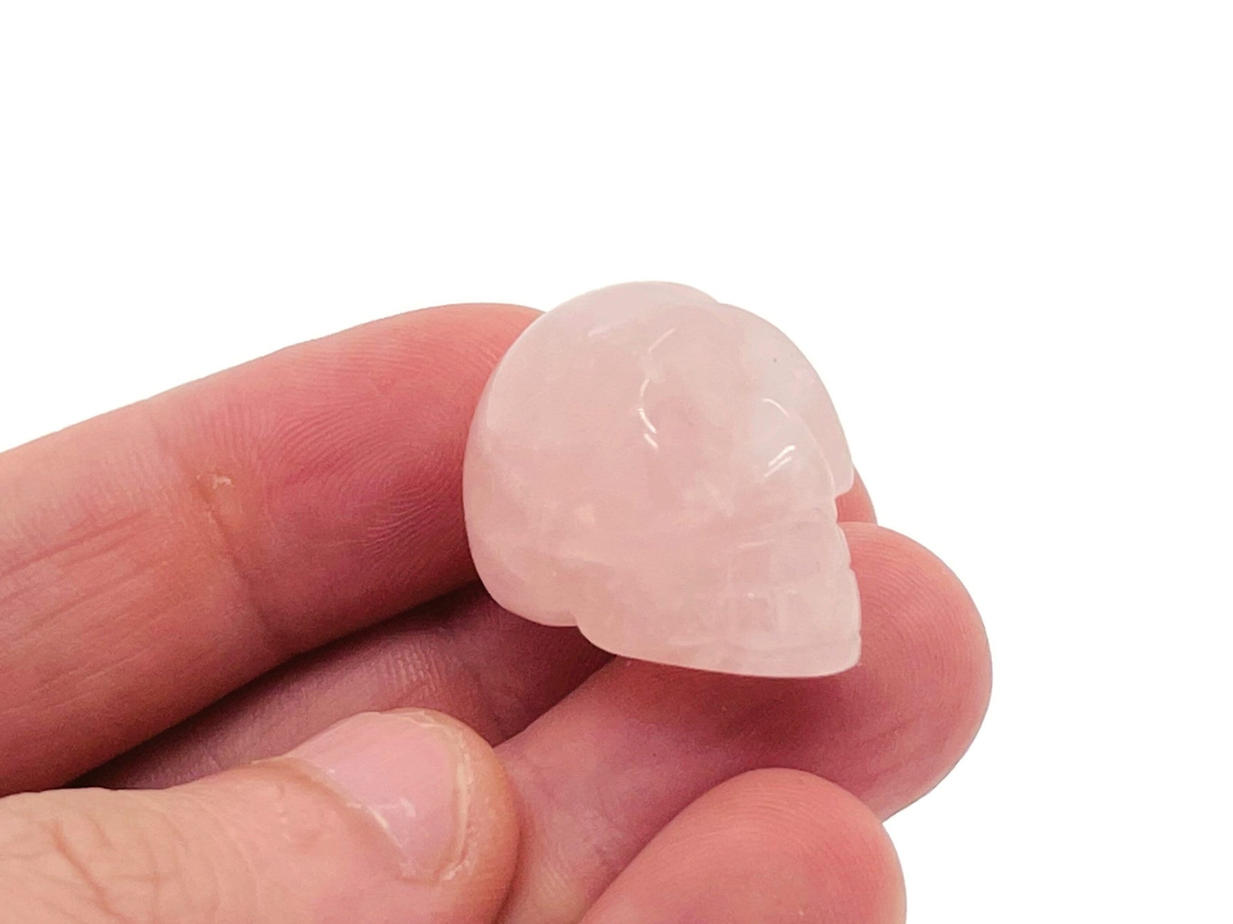 Pink rose quartz skull carved gemstone, 25mm, showcasing detailed craftsmanship and smooth polished surface.